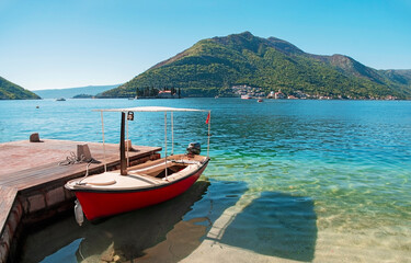 Fototapeta na wymiar Red boat in the Bay of Kotor in the city of Perast