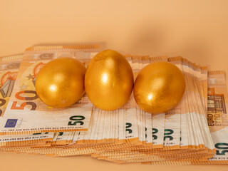 Golden eggs on money. Golden chicken eggs and euro banknotes.