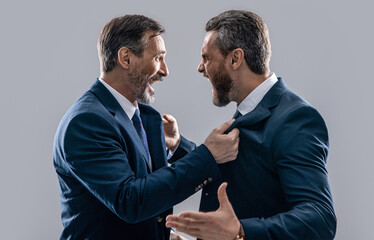 two arguing businessmen shout in conflict isolated on grey background. businessmen have conflict