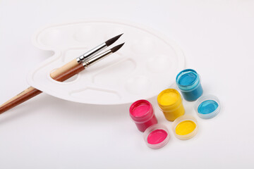 Acrylic paints in boxes, brushes and white palette.