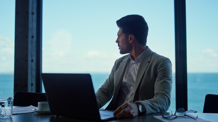 Young businessman looking panorama window. Concerned boss relaxing after work