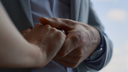 Fototapeta premium Lovely couple hands connecting in cloudy sky background. Unity and love
