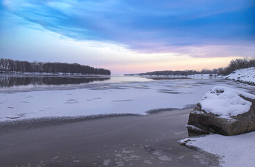 View down a river in early winter as ice begins forming on the calm water, colourful sunrise sky, nobody