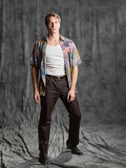 A relaxed dude in a colorful shirt and a white T-shirt, posing in the studio on a gray background