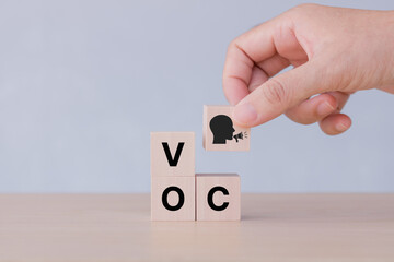 Voice of customer concept. Customer centric. Hand holds wooden cubes with "VOC" icon on grey background ,copy space. Consumer feedback, marketing communication. Improve and develop product, service.