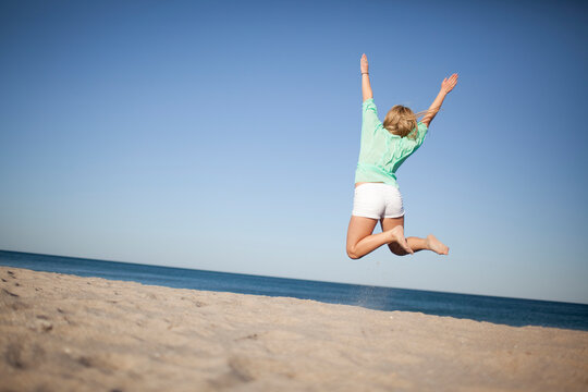 Back View of Young Woman Jumping on Beach, Palm Beach Gardens, Palm Beach County, Florida, USA