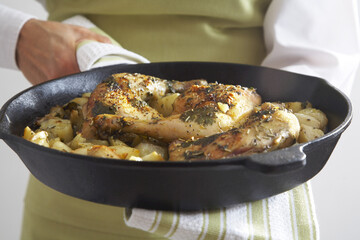 Close-up of Roasted Chicken Legs, Roasted Onions and Potatoes in Cast Iron Skillet