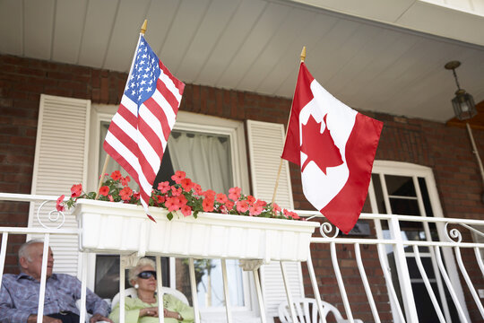 Senior Couple on Front Porch with American and Canadian Flags