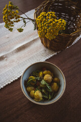 flatlay of potato stir-fried dish - natural linens and fresh herbs on a wooden table - healthy vegetarian dish