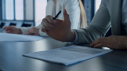 Closeup businessman hand holding pen reading contract agreement in office.