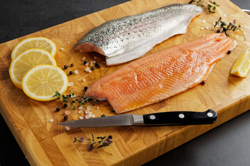 Fresh trout fillets with skin on a wooden cutting board, prepared for frying. - obrazy, fototapety, plakaty