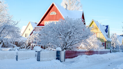 Winter fairy-tale landscape on the street with houses with a triangular roof and roads covered with...