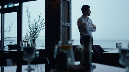 Focused entrepreneur silhouette resting cozy panoramic lounge restaurant alone