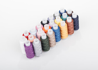 soft focus. shallow depth of field. the background is white. a set of multicolored sewing threads.