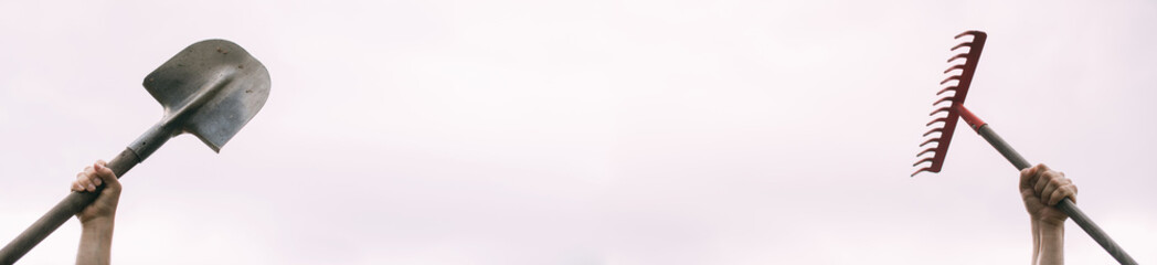 A man's hand holds a rake on a white background. Garden tools isolated on a neutral background.