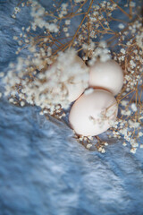 Easter eggs on a gray fluffy background. Easter holiday concept. Grey background. Gypsophila flowers. Vertical photography.
