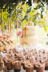 cake for the celebration of a first communion on a table full of desserts with decoration of roses,...