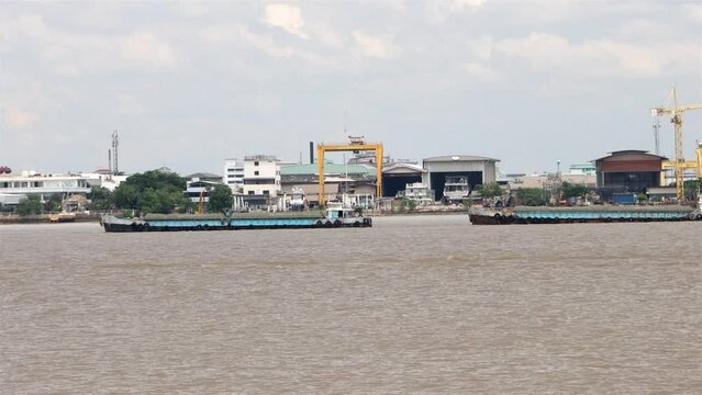 A group of boats tied in a row is pulled with cargo up the Chao Phraya River, Samut Prakan, Thailand, accelerated video