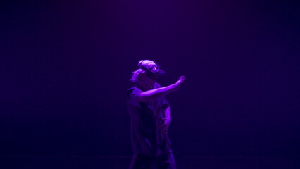 Vr guy dancing headset in dark neon room. Energetic player experiencing hi tech