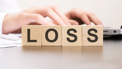 man made word LOSS with wood blocks on the background of the office table. selective focus. business concept.