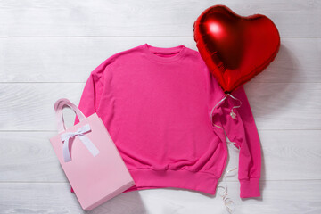 Pink sweatshirt mockup. Valentines Day concept shirt, balloons heart shape on wooden background....