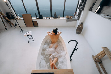 Relaxed lady taking bath, enjoying and relaxing while lying in bathtub, top view