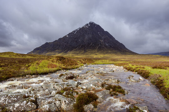 River Etive and mountain range Buachaille Etive Mor with dark cloudy sky at Glen Coe in Scotland, United Kingdom
