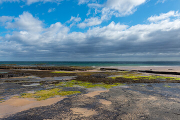 Rocky beach with dramatic clouds over the North Sea at Bamburgh in Northumberland, England, United Kingdom