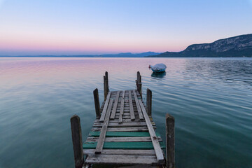 Old wooden jetty on the Lake Garda (Lago di Garda) at dawn in Garda in Veneto, Italy