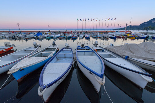 Harbor marina with rows of docked fishing boats Lake Garda (Lago di Garda) at dawn in Garda in Veneto, Italy