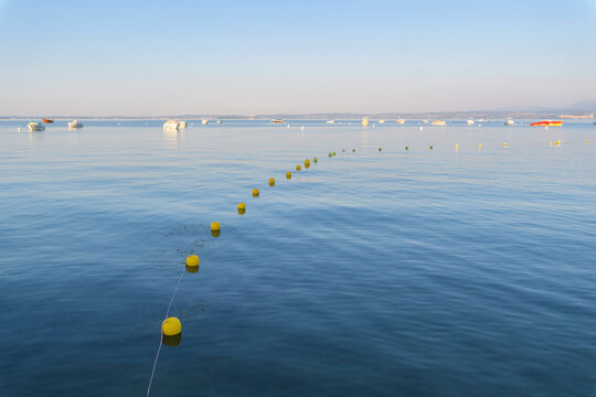 Lake Garda (Lago di Garda) with line of buoys and boats anchored in the distance at Bardolino in Veneto, Italy