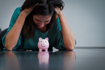 negative thinking woman with dark hairs looking depressed to her pink piggy bank while being scary...