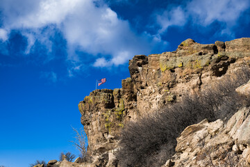 2022-12-22 A JAGGED ROCK FACE WITH THE AMERICAN FLAG AND A CLOUDY SKY IN CASTLE ROCK