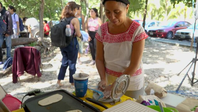 Yucatecan Woman in Traditional Mayan Huipil Clothing Making Tlayudas with Her Hands and Corn Dough on an Electric Grill. Pre-Hispanic Oval Shaped Mexican Dish Made of Masa like Quesadillas Huaraches