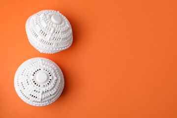 Laundry dryer balls on orange background, flat lay. Space for text