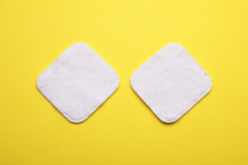 Soft clean cotton pads on yellow background, flat lay
