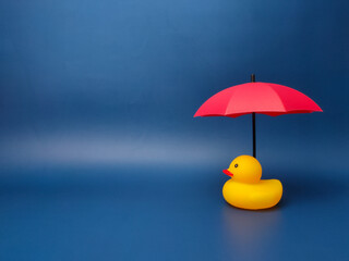Red umbrellas and yellow ducks on a blue background. The concept of insurance coverage.