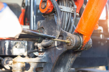 hand of a workman greasing the grease nipple of a hydraulic cylinder the backhoe. Routine Repair...