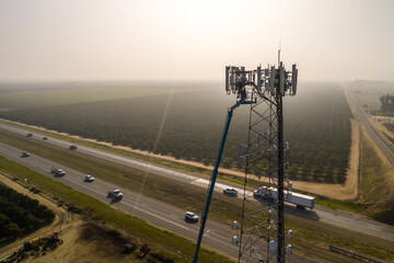 Climbers check antennas on tower. Tower is being checked on highway background.
