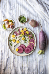 Radishes and onions on a white plate with a textured white towel - healthy food ingredient photo
