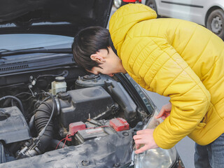 Fototapeta na wymiar A young caucasian guy in a yellow jacket inspects the internal breakdown of the front headlight