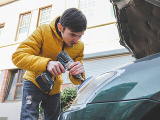 Men are polishing the headlight of a car with a drill and a sponge disk.