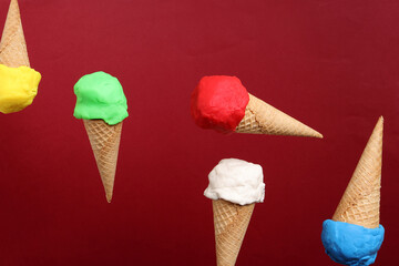 Fake modelling clay multi colourful ice cream on red biscuit cone drop fly fall on white background