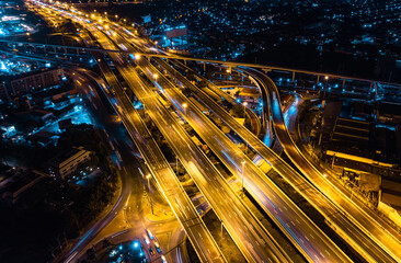 Fototapeta na wymiar Aerial top view of Modern Multilevel Motorway Junction with Expressway, Road traffic an important infrastructure in Thailand. Bangkok urban Mass Transit Project (Pink Line Monorail). Night scene.