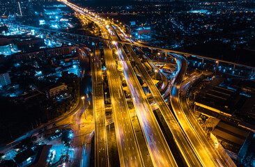 Aerial top view of Modern Multilevel Motorway Junction with Expressway, Road traffic an important infrastructure in Thailand. Bangkok urban Mass Transit Project (Pink Line Monorail). Night scene.