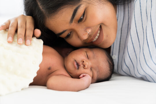 African American Mother Kissing Her Newborn Baby On Bed. Young Mom Or Nurse Taking Care Newborn In The Hospital