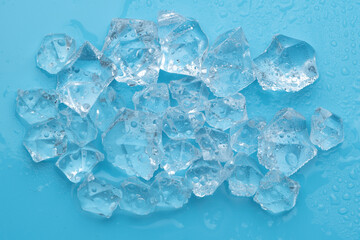 Ice cubes and ice shards with water drops on a blue background. The concept of cold and freshness