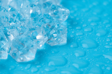Ice cubes and ice shards with water drops on a blue background. The concept of cold and freshness