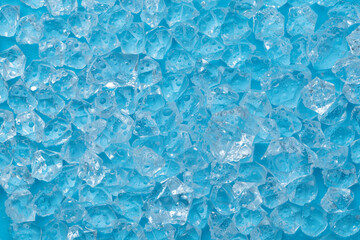 Ice cubes and ice shards with water drops on a blue background. The concept of cold and freshness