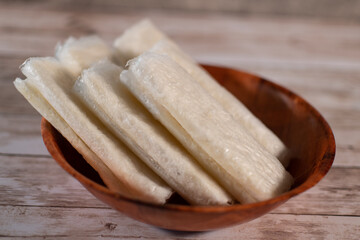 Pootharekulu or putharekulu  a famous sweet from Andhra Pradesh , India made with rice pure ghee and sugar.  A paper thin sweet served in a wooden bowl front view